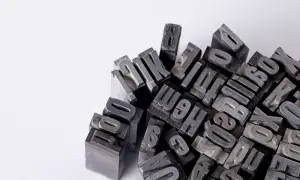 Stos metalowych czcionek drukarskich, tworzących chaotyczny, ale intrygujący wzór.