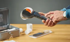 Ręce obsługują kasę fiskalną z rolką paragonu. To kluczowy element visual marketing, ułatwiający transakcje.