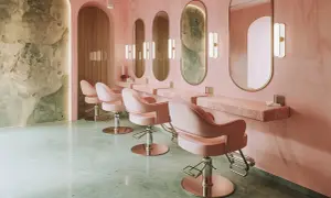 Eleganckie fotele w salonach kosmetycznych, różowe wnętrze z marmurowymi blatami i lustrami.