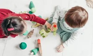 Dzieci bawią się drewnianymi zabawkami, tworząc scenkę z dinozaurami. Idealne reklamy zabawek dla małych odkrywców.