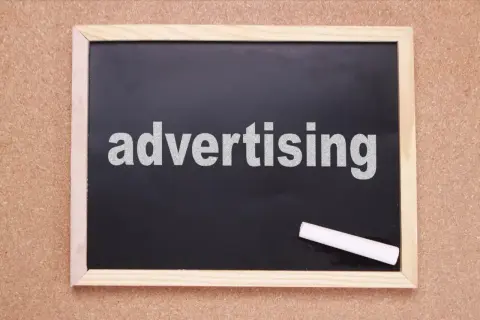 Tablica z napisem "advertising" i kredą. Czas na rymowane hasła reklamowe, które przyciągną uwagę!
