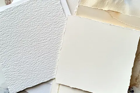 Stos różnych rodzajów papieru, w tym biały, fakturowany papier i kremowy papier o postrzępionych krawędziach. Idealny do sztuki i rękodzieła.