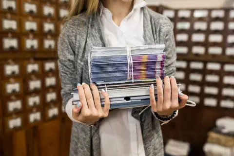 Kobieta trzyma stos książek i broszur, gotowych do wysyłki dzięki usłudze print on demand.
