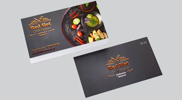 Wizytówki restauracji Red Hot Chilli Pepper z lśniącym, miedzianym logo i zdjęciem potrawy. To przykład, co to jest laminat – nadaje elegancji i trwałości.