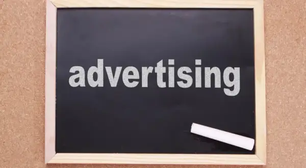 Tablica z napisem "advertising" i kredą. Czas na rymowane hasła reklamowe, które przyciągną uwagę!