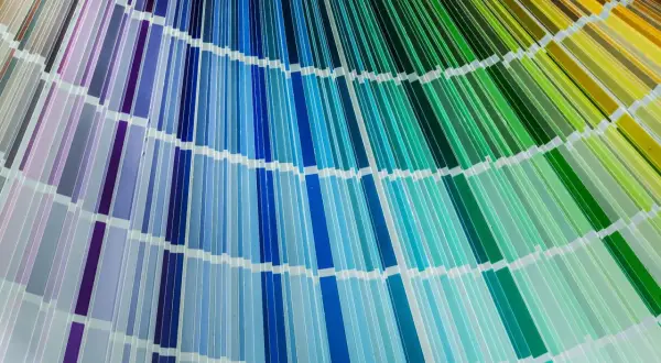Rozłożona paleta kolorów cmyk, ukazująca szeroką gamę odcieni fioletów, błękitów, turkusów i zieleni, tworząc tęczowy wachlarz.