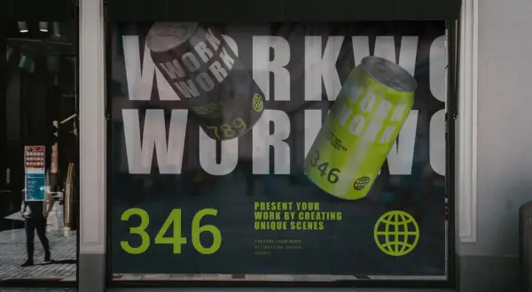 Reklama na witrynie z hasłem "WORK" i puszkami napoju. Folia OWV co to? To materiał na okna, idealny do takich kreatywnych prezentacji.