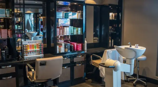 Nowoczesny salon fryzjerski. Reklama usług i produktów Kérastase. Fotele, umywalki i bogaty wybór kosmetyków.
