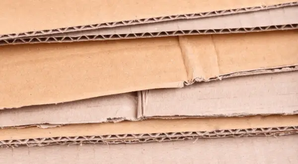 Warstwowa struktura kartonu, ukazująca różne rodzaje tektury falistej i płaskiej, gotowe do recyklingu.
