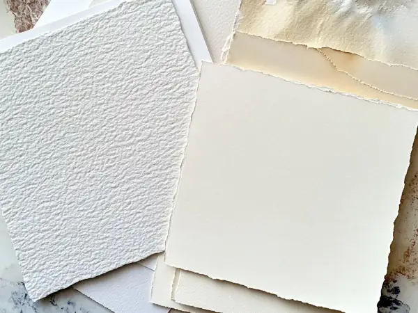 Stos różnych rodzajów papieru, w tym biały, fakturowany papier i kremowy papier o postrzępionych krawędziach. Idealny do sztuki i rękodzieła.
