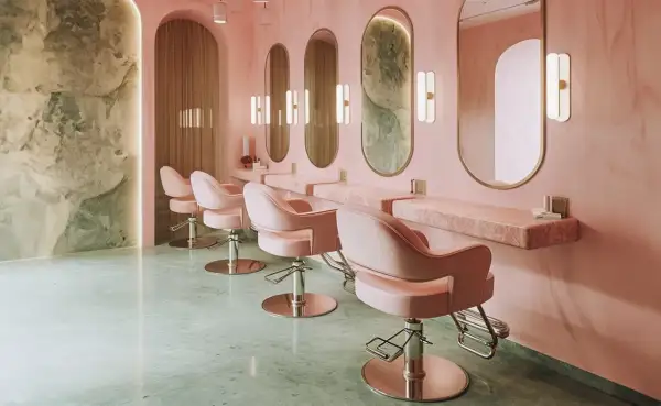 Eleganckie fotele w salonach kosmetycznych, różowe wnętrze z marmurowymi blatami i lustrami.