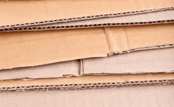 Warstwowa struktura kartonu, ukazująca różne rodzaje tektury falistej i płaskiej, gotowe do recyklingu.