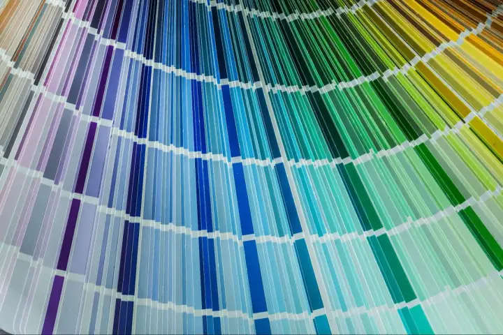Rozłożona paleta kolorów cmyk, ukazująca szeroką gamę odcieni fioletów, błękitów, turkusów i zieleni, tworząc tęczowy wachlarz.
